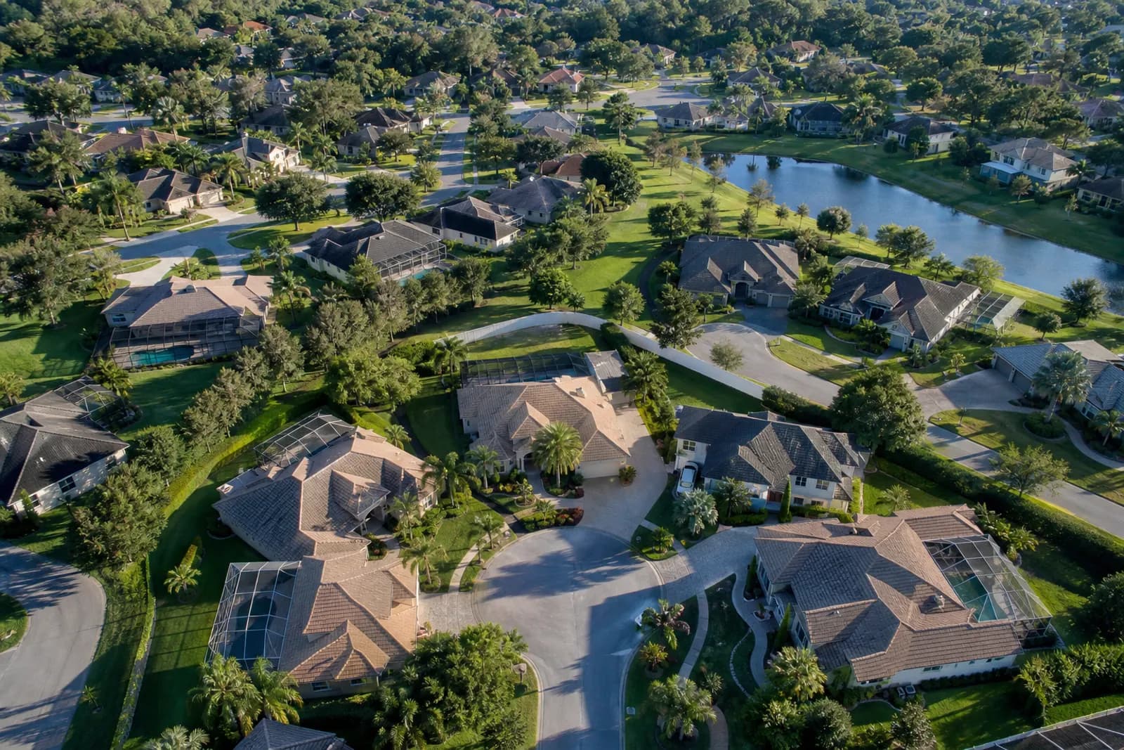 Aerial view of a residential neighborhood with tree-lined streets and a lake.